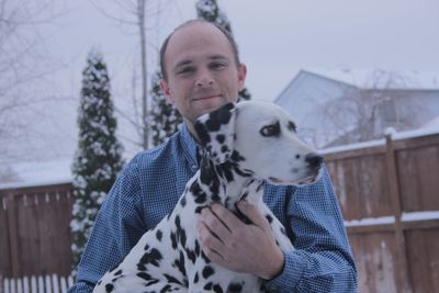 Portrait of man holding dalmatian during winter