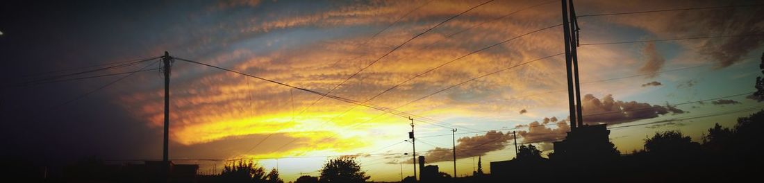 Low angle view of power lines against cloudy sky