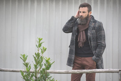 Hipster with hands in pockets against wall