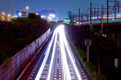 Light trails on road in city against sky at night