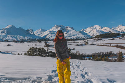 A full-body shot of a young caucasian woman walking towards the camera in the french alps mountains