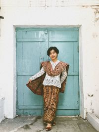 Young woman standing against wall