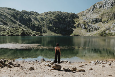 Woman looking lake while standing on stone during sunny day