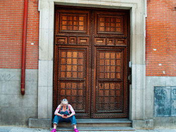 Full length of woman sitting outside building