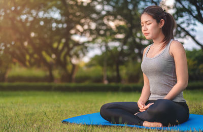 Beautiful young woman sitting on seat in park