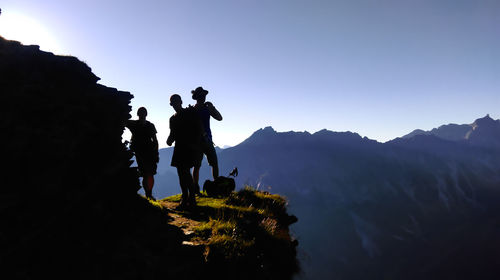 Silhouette of men standing on mountain against sky