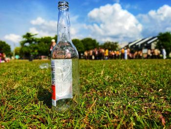 Close-up of water bottle on grass in field