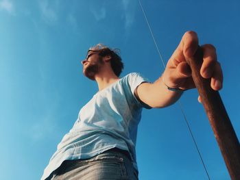 Low angle view of man holding stick against sky