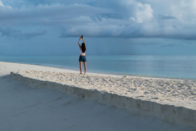 Rear view of man on beach against sky