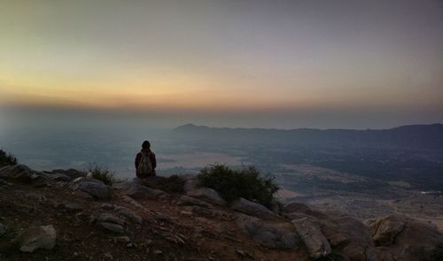 Nature theories, pushkar, india-woman sitting on rock against sky during sunset