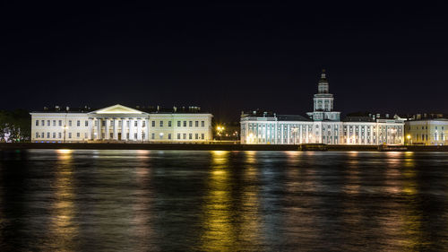 Illuminated buildings by river at night