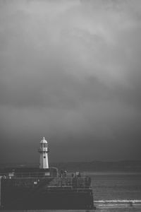 Lighthouse by sea against sky