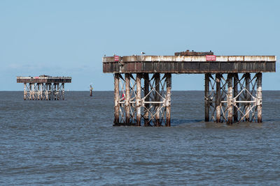 Pier over sea against clear blue sky