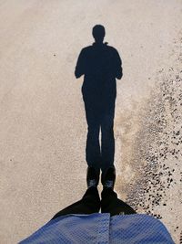 Low section of man standing on sand