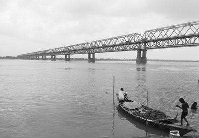People on bridge over river against sky