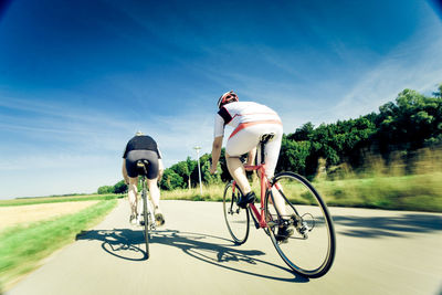 Man riding bicycle on road against sky