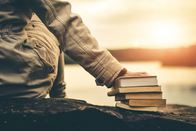Midsection of man holding book against sky