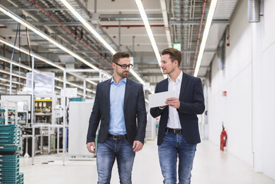 Two men with tablet talking in factory shop floor