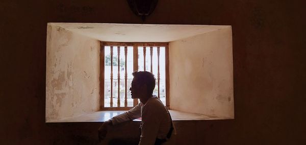 Man looking away while sitting by window