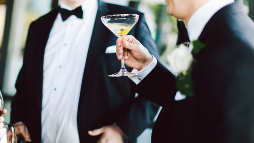 Midsection of men holding drinks in ceremony