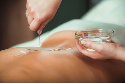 Massage oil. therapist pouring aromatic massage oil onto womans back