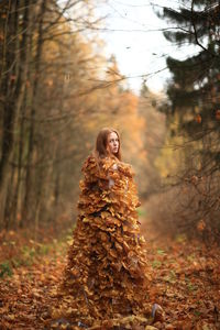 Portrait of young woman standing in forest during autumn