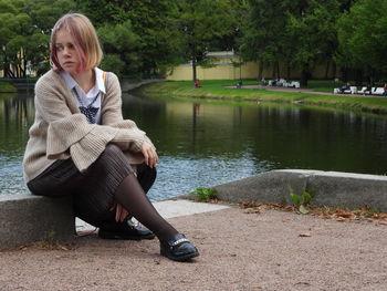 Woman sitting by lake in park