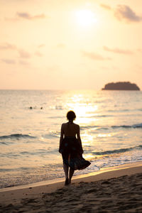 Rear view of man standing on beach during sunset