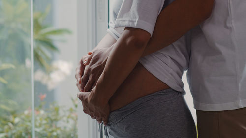 Midsection of man holding stomach of pregnant woman