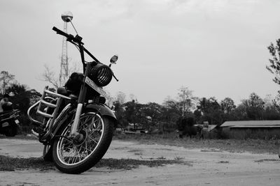 Bicycle on road by field against sky