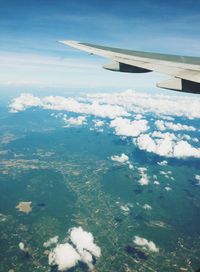 Aerial view of airplane wing over landscape against blue sky