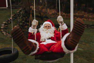 Man wearing santa costume swinging in garden