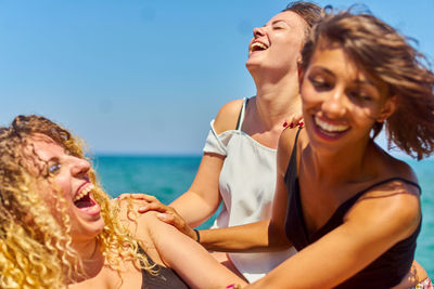 Happy friends at beach against sky