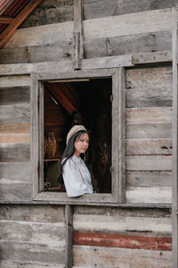 Portrait of young woman looking through window