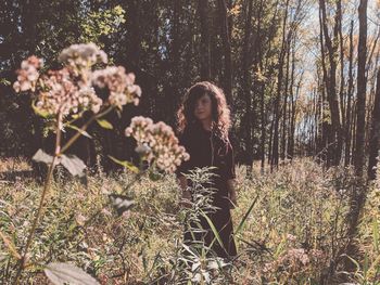 Cute girl standing amidst plants and trees in forest