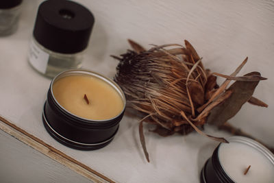 Mockup of homemade wax candles on a white shelf with dried flowers. minimalism in interior details