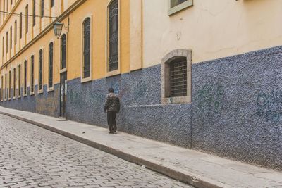 Rear view of man walking next to a colorful building in la paz, bolivia