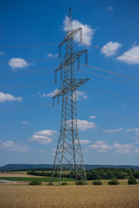 Low angle view of electricity pylon on field against sky