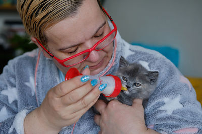 Portrait of a middle aged woman feeding a cute kitten with a milk bottle