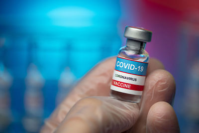 Close-up of hand holding bottle against blurred background