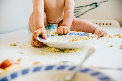 Low section of baby girl eating food on table at home
