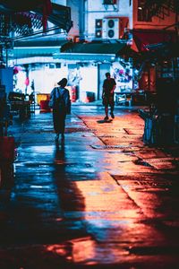 Rear view of people walking on street in rain