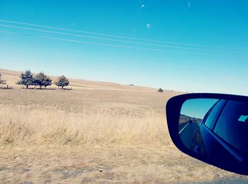 Vehicle on landscape against clear blue sky