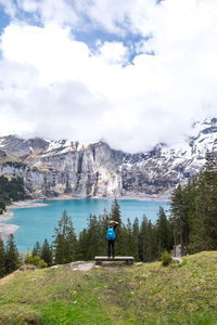 Rear view of man standing by lake against sky