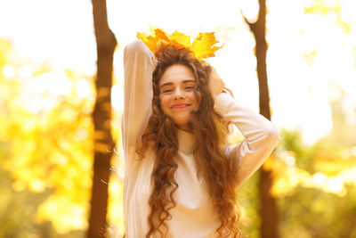 Portrait of young woman standing against tree