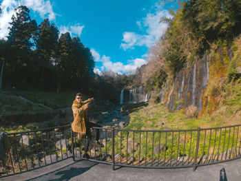 Woman standing by railing against trees