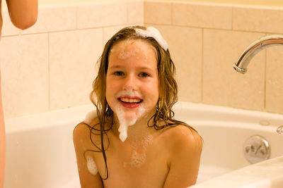 Portrait of smiling girl sitting in bathtub