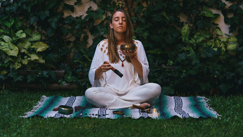 Young woman looking away while sitting on field