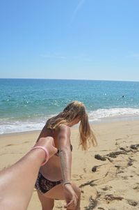 Midsection of woman on beach against sky