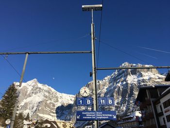 Low angle view of snowcapped mountains against clear blue sky